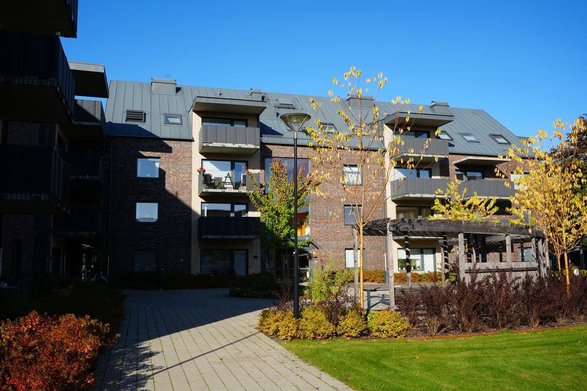 Gångväg, träd och grön gård vid trygghetsboendet Uttern.